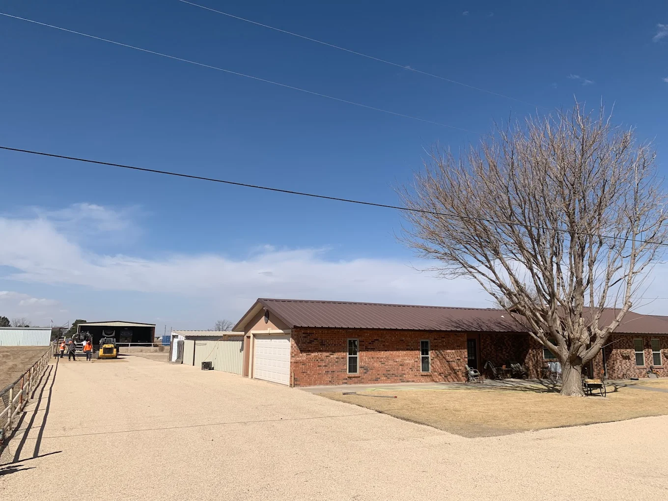 Rural ranch property with a paved access drive under a big sky