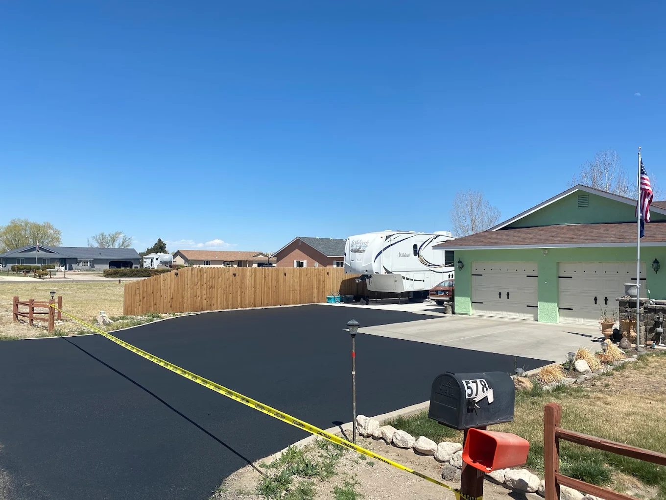 Fresh black asphalt driveway with an RV parked in fall foliage